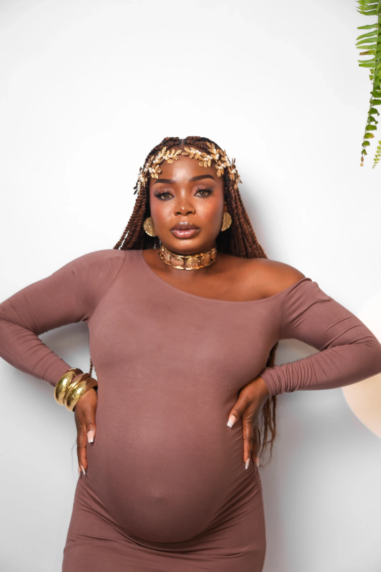 Gladys Ojonugwa gestante com tiara dourada e mãos na cintura