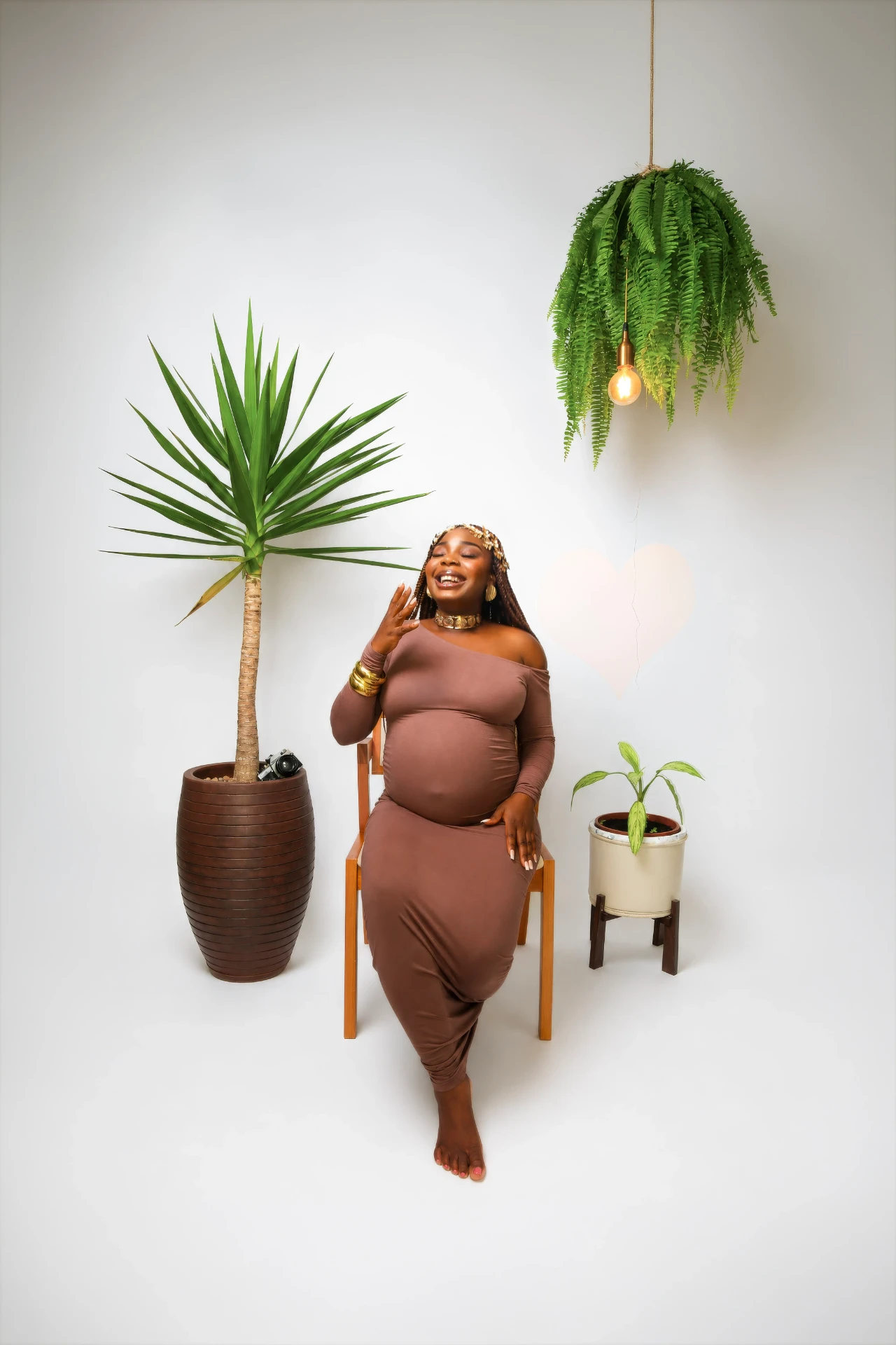 Gladys Ojonugwa gestante sentada sorrindo entre plantas
