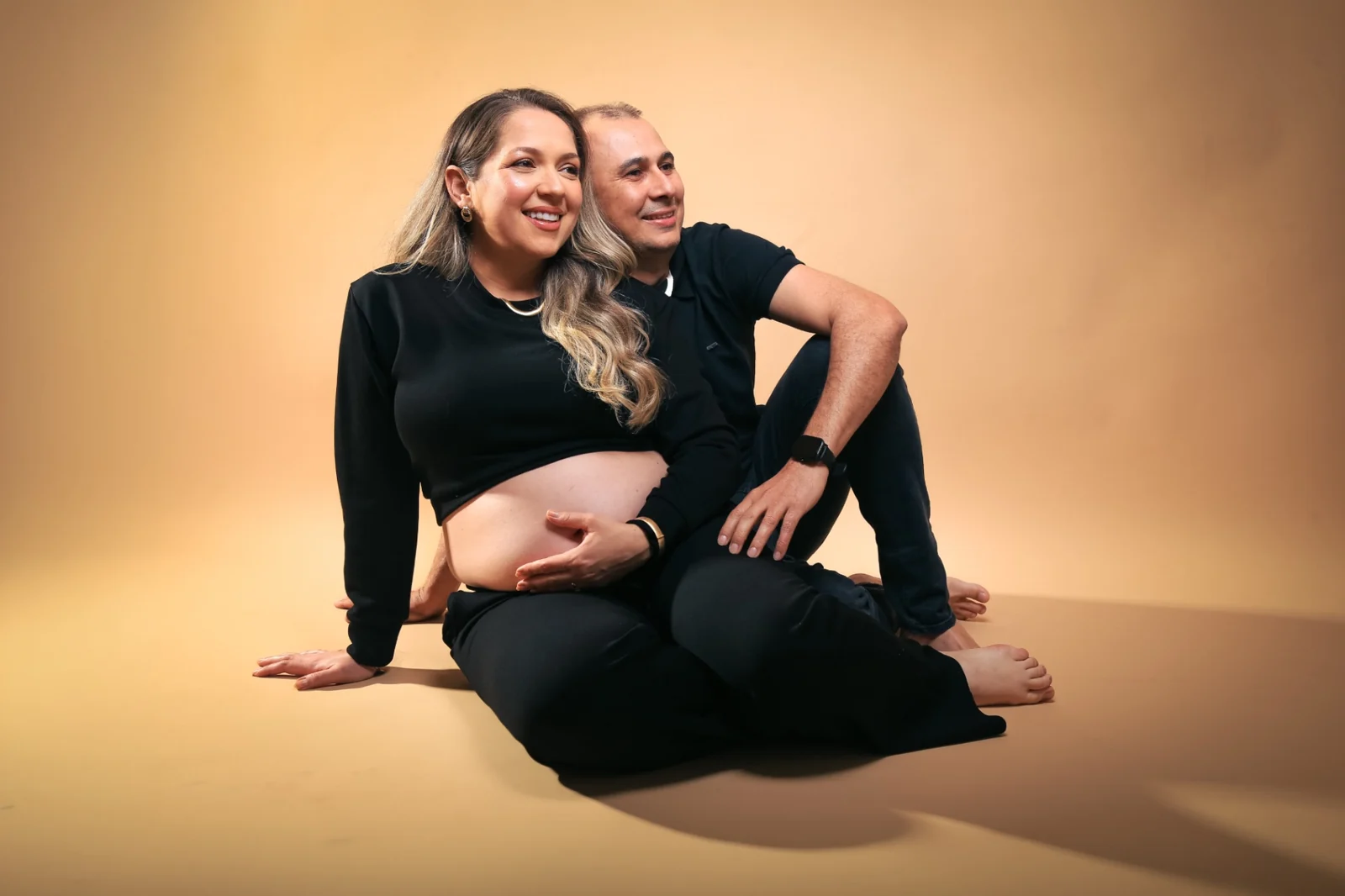 Deborah e Wellington sentados juntos de roupa preta em fundo quente