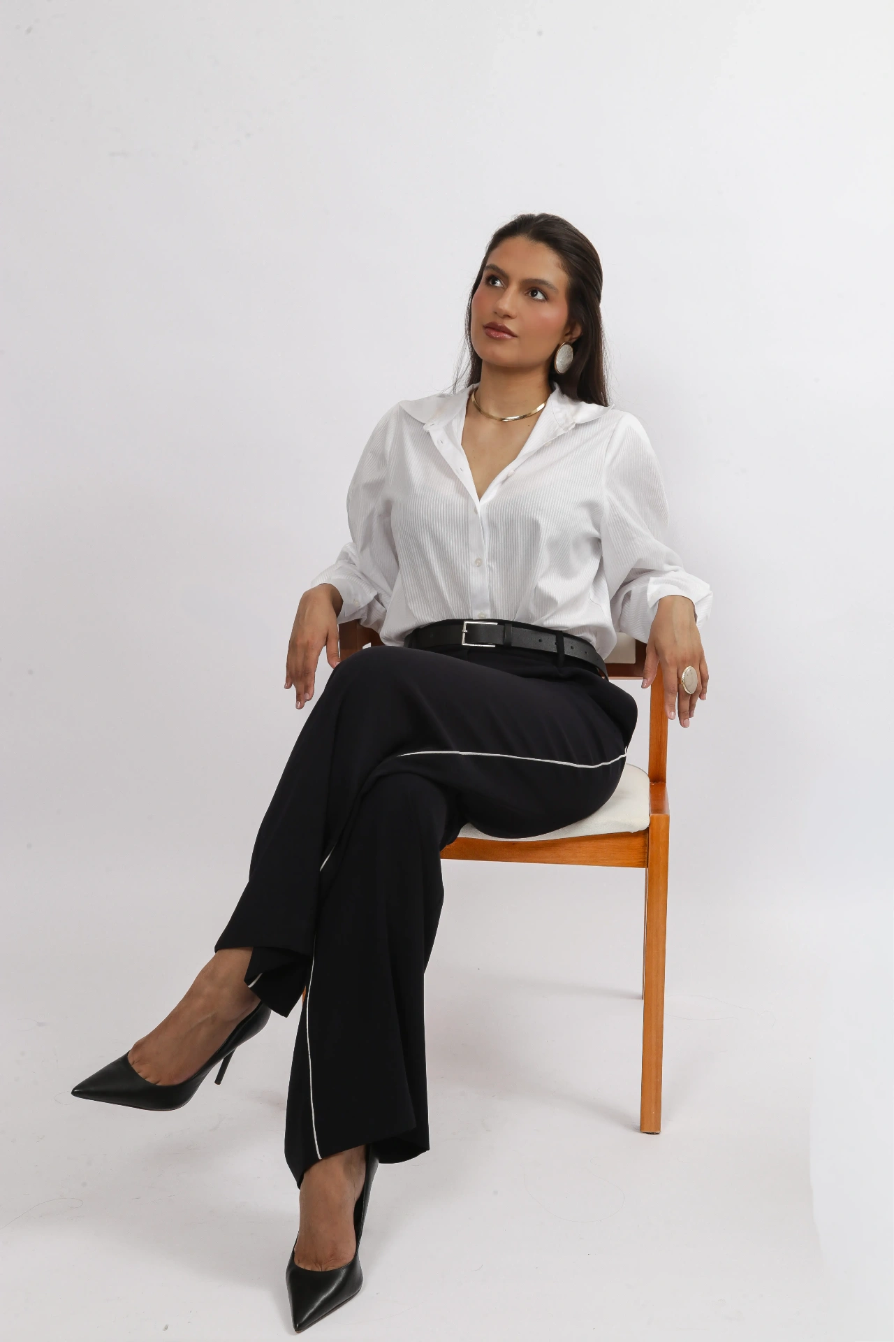 Amanda Siara sentada na cadeira com pernas cruzadas e scarpin preto