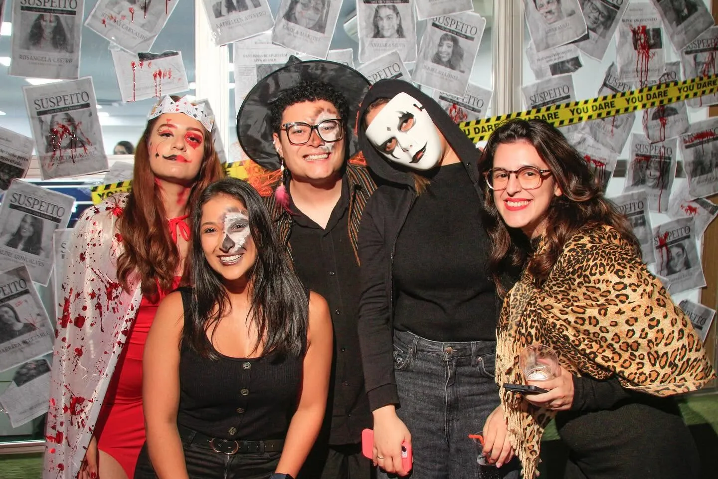 Omnibees Halloween — grupo posando com murais de suspeitos ao fundo