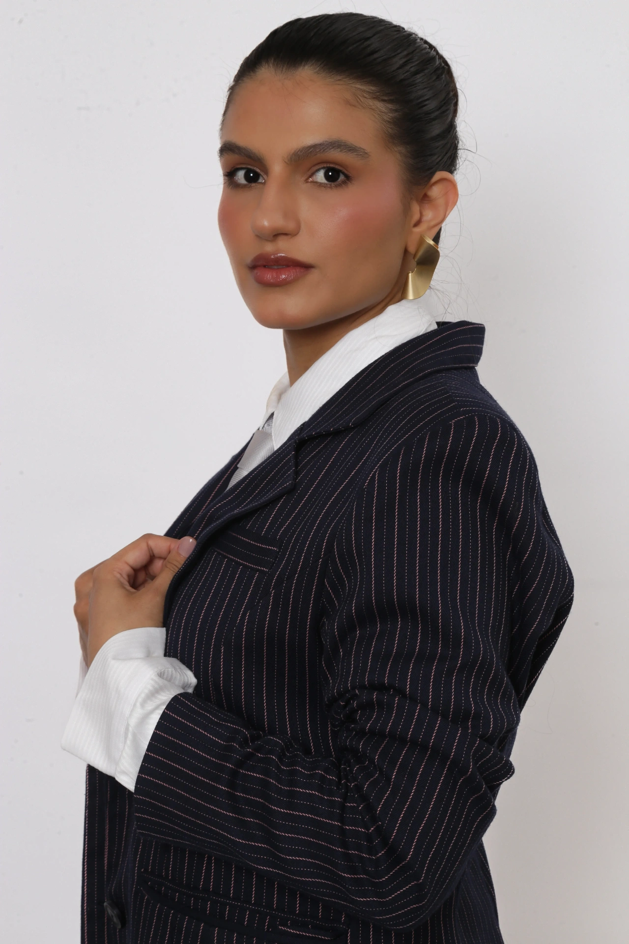 Amanda Siara olhando para a câmera com coque e blazer risca de giz