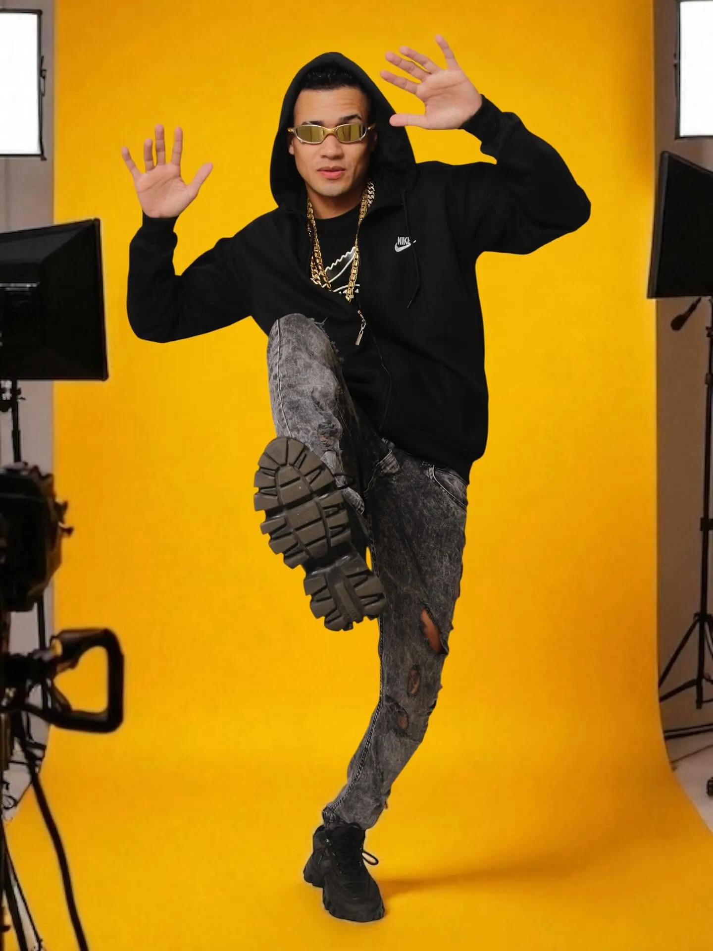 Dj Elerson — pose dinâmica com moletom Nike e corrente dourada em fundo amarelo