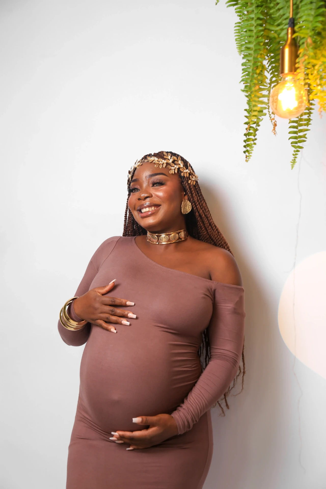 Gladys Ojonugwa gestante sorrindo sob luminária de estúdio