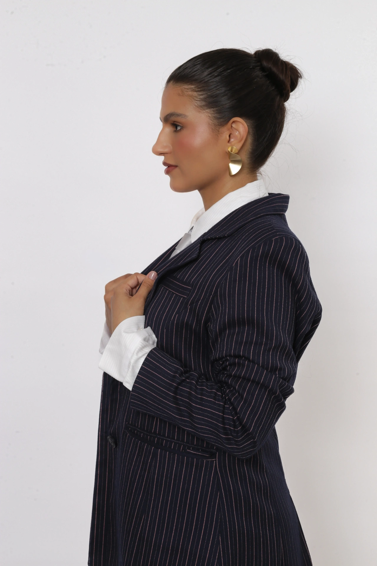 Amanda Siara de perfil ajustando o blazer risca de giz