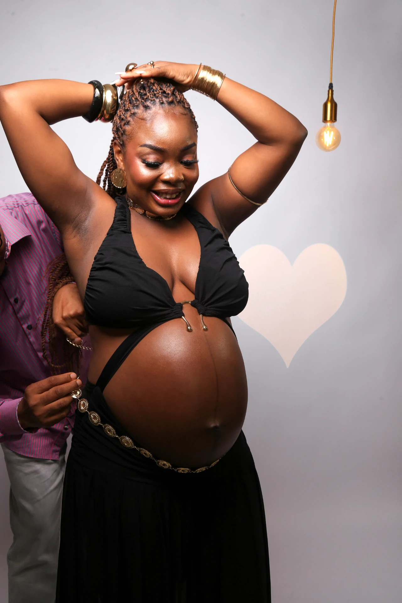 Gladys Ojonugwa gestante sorrindo com o companheiro ao fundo
