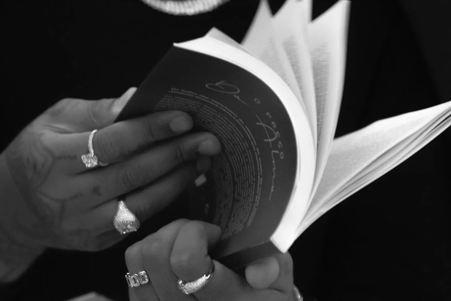 Lançamento do livro O Preço da Alma — close em preto e branco das mãos folheando o livro