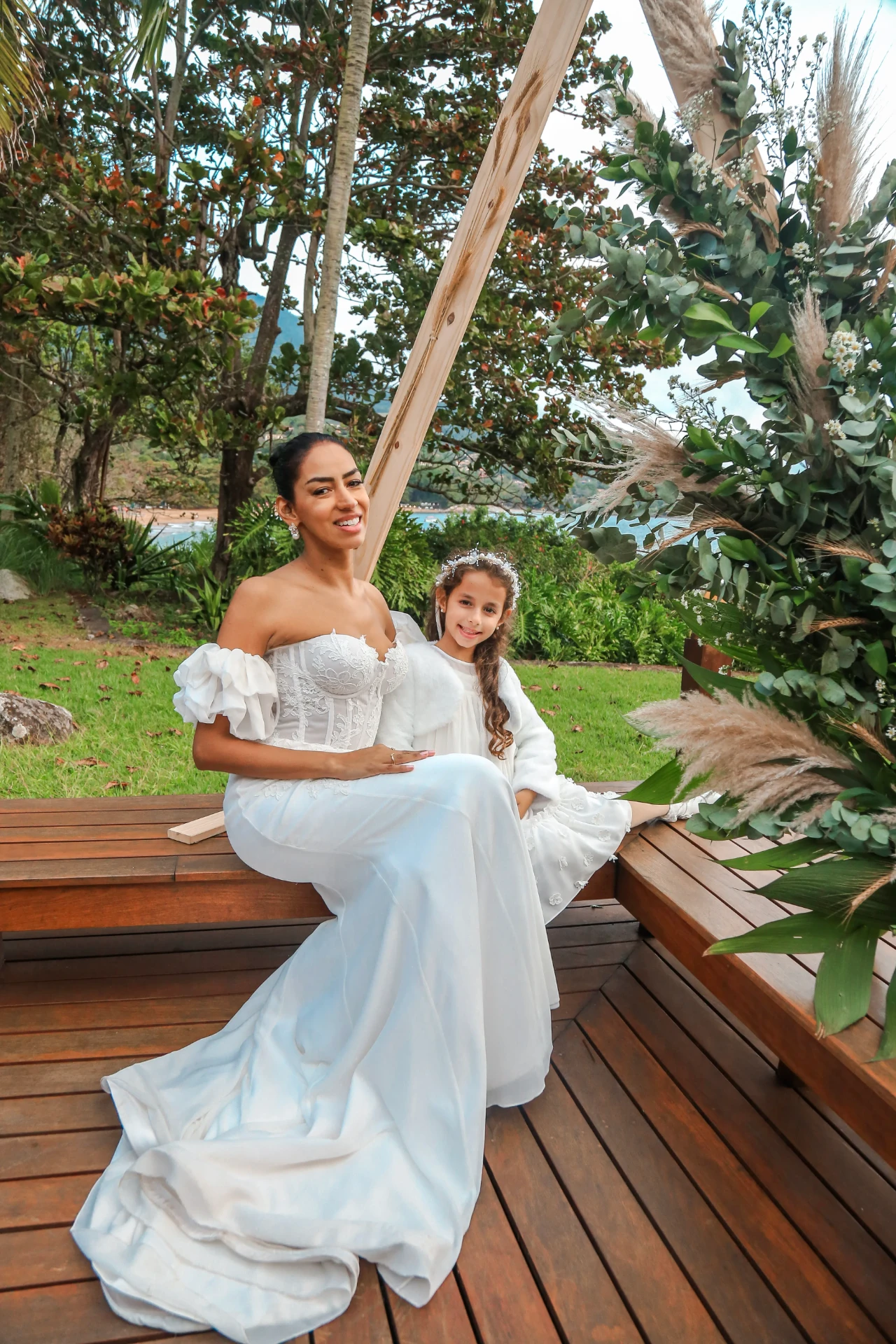 Larissa e Roberto — noiva sentada no deck com a daminha de honra