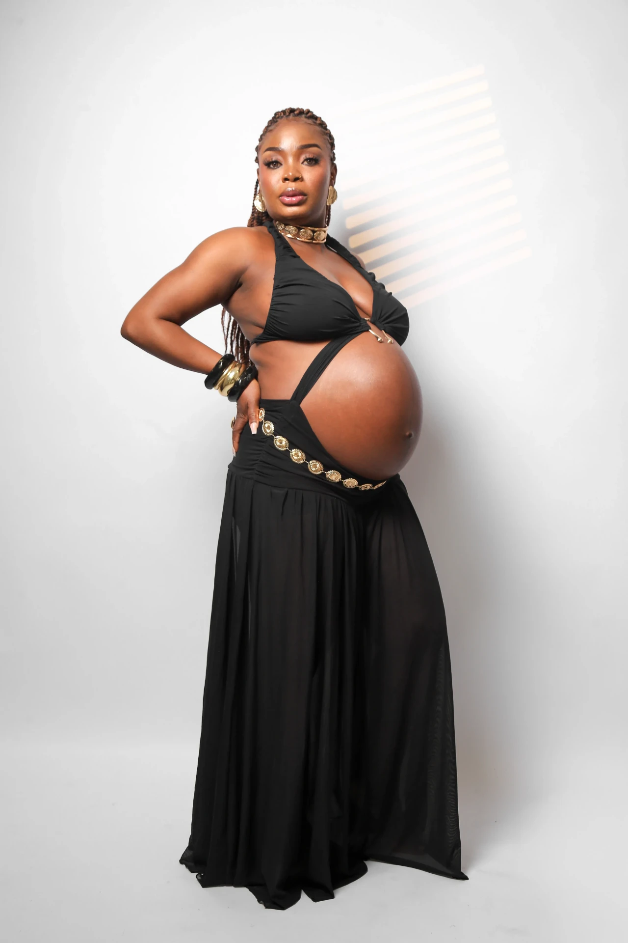 Gladys Ojonugwa gestante em look preto com cinto dourado