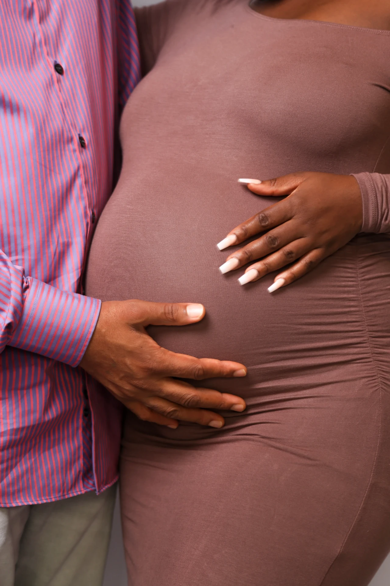 Detalhe das mãos do casal sobre a barriga