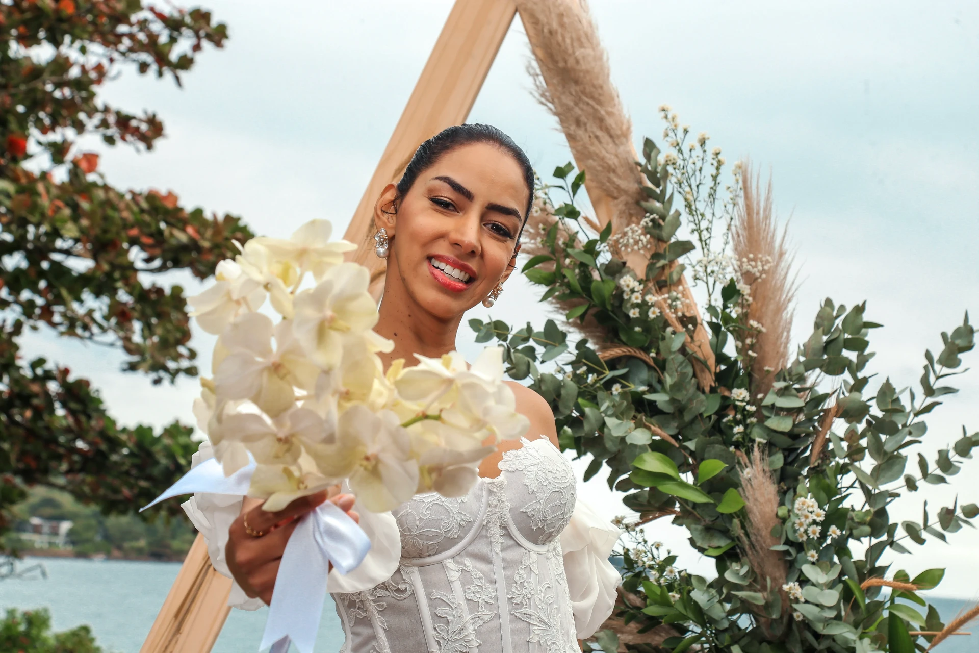 Larissa e Roberto — retrato da noiva sorrindo segurando o buquê de orquídeas