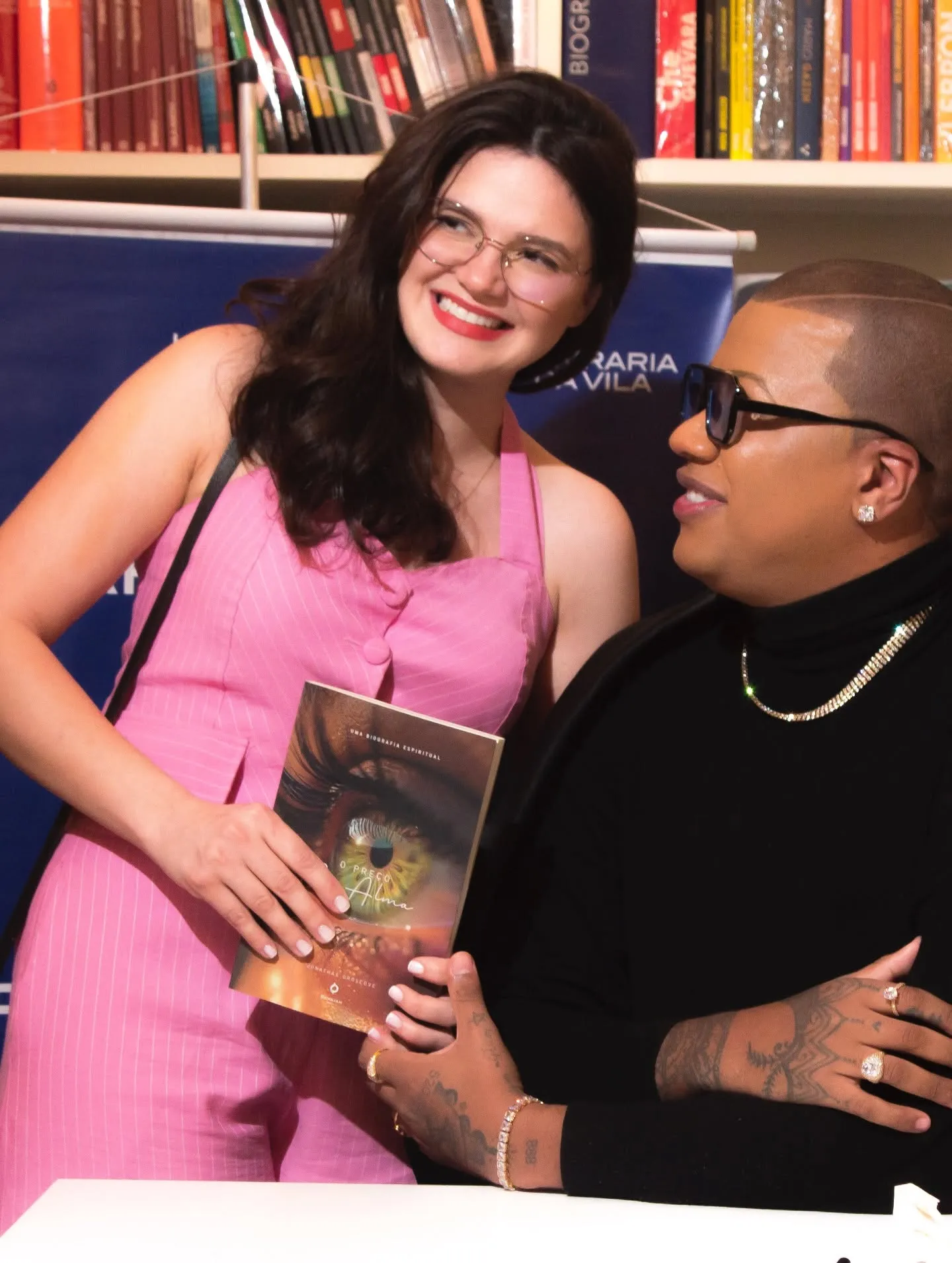 Lançamento do livro O Preço da Alma — autora convidada de vestido rosa com o livro