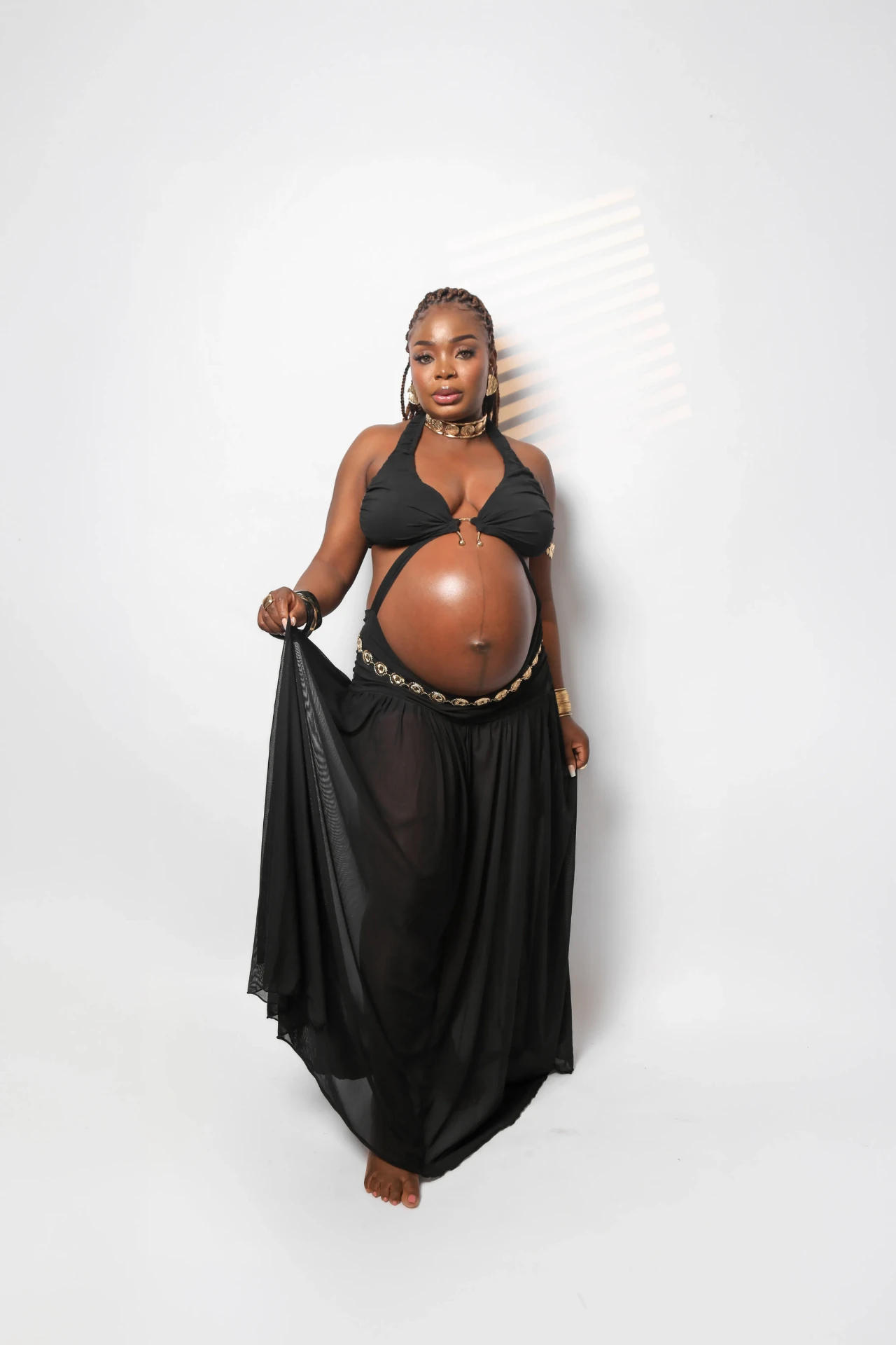 Gladys Ojonugwa gestante em pé segurando o vestido preto