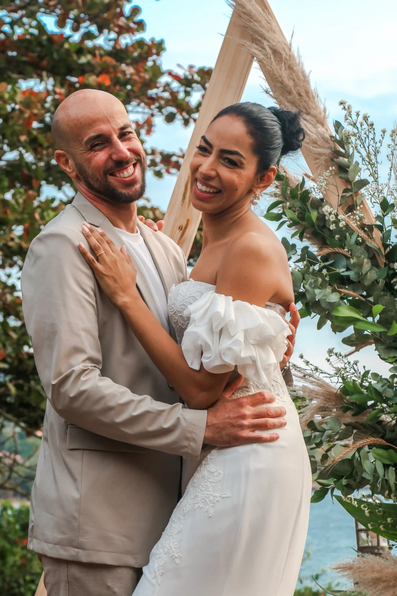 Larissa e Roberto — noivos abraçados sorrindo diante do altar triangular