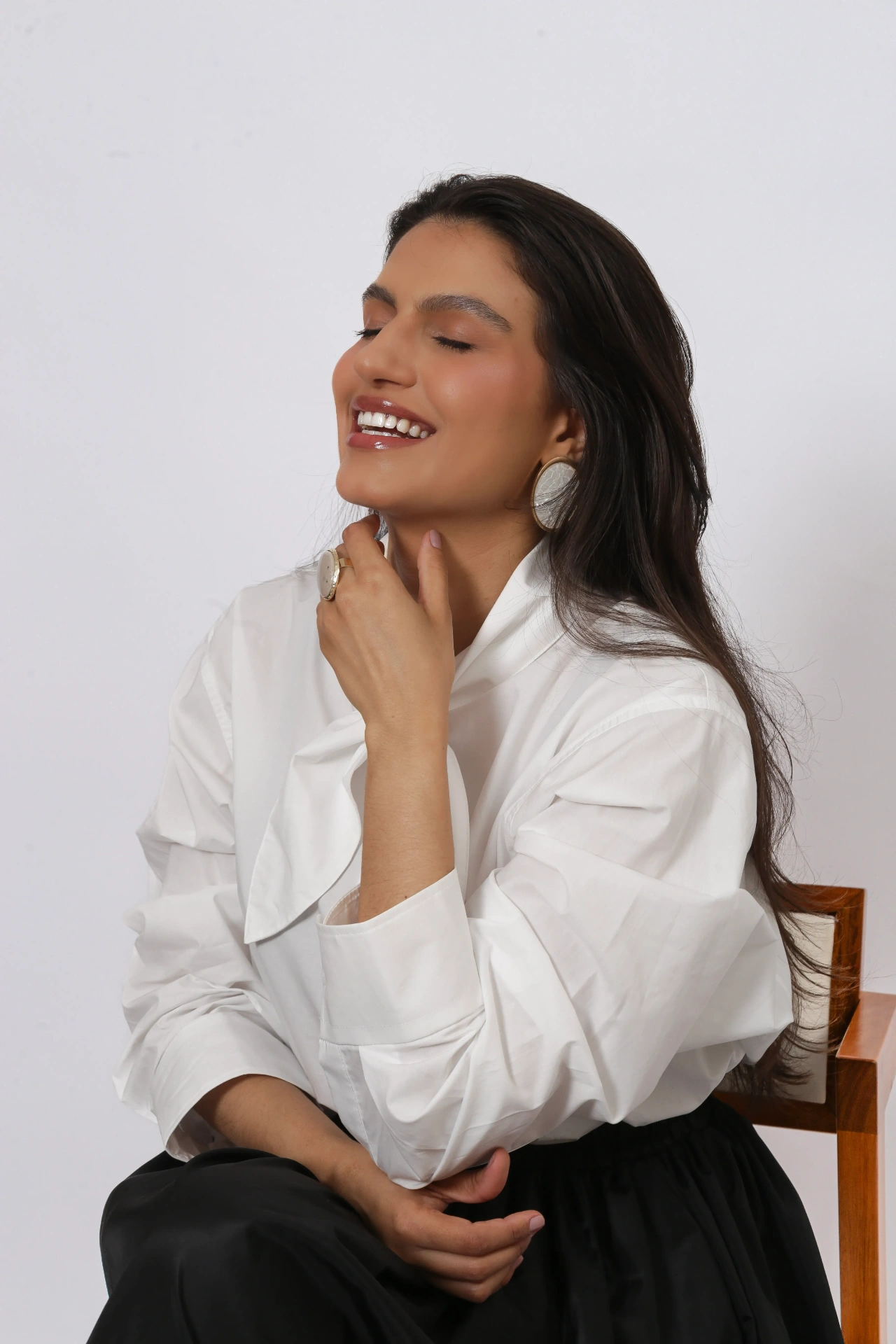 Amanda Siara sorrindo sentada em cadeira de madeira