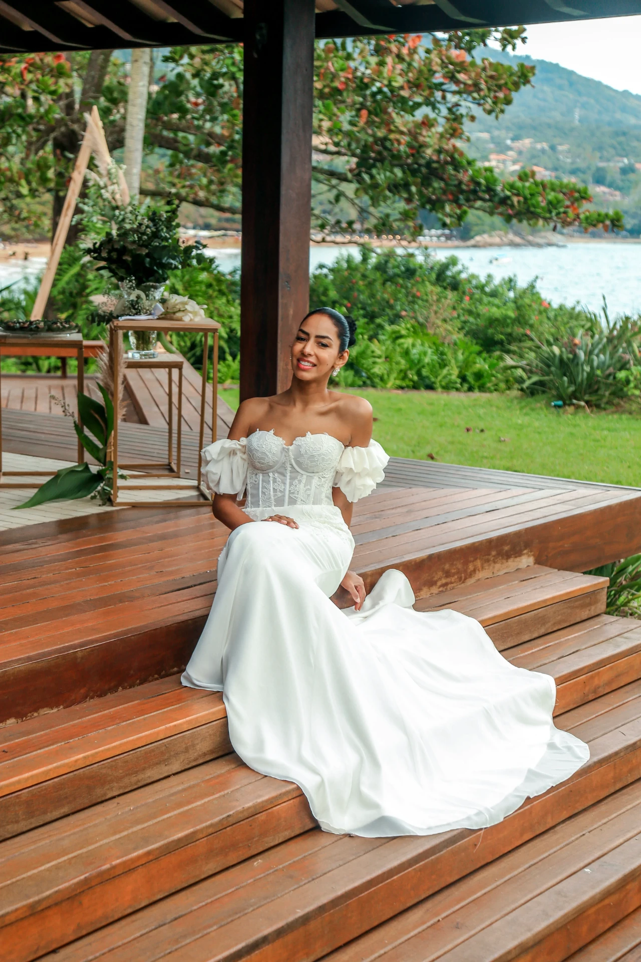 Larissa e Roberto — noiva sentada no deck de madeira com o mar ao fundo