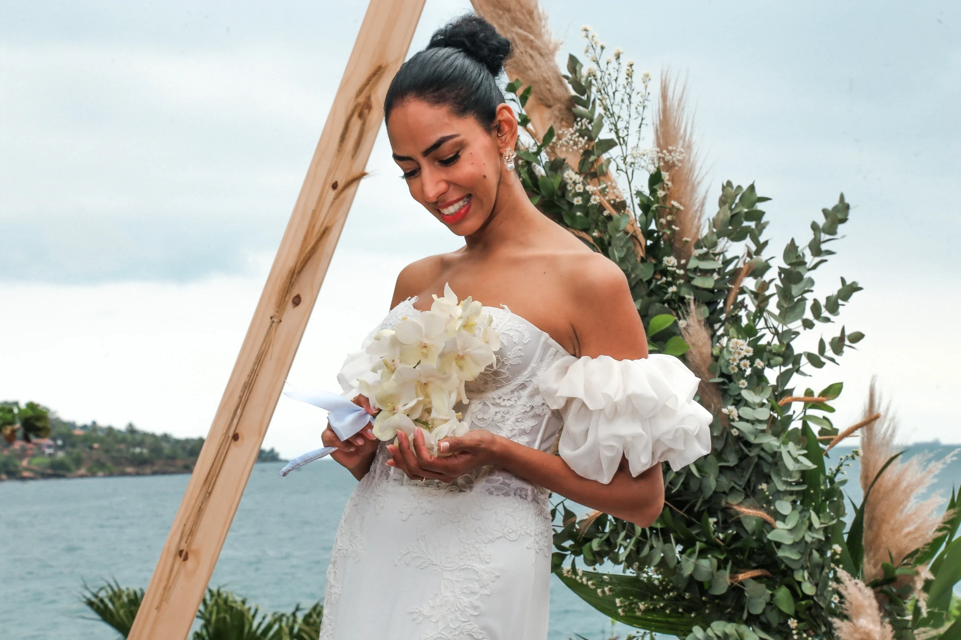 Larissa e Roberto — noiva olhando para o buquê de orquídeas brancas