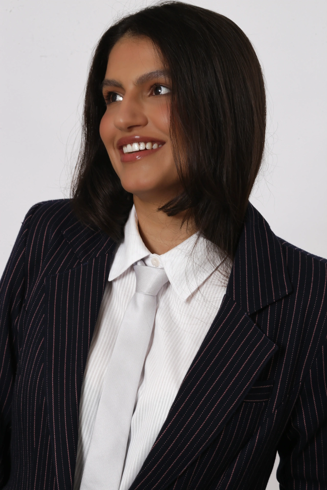 Amanda Siara sorrindo em close com blazer risca de giz