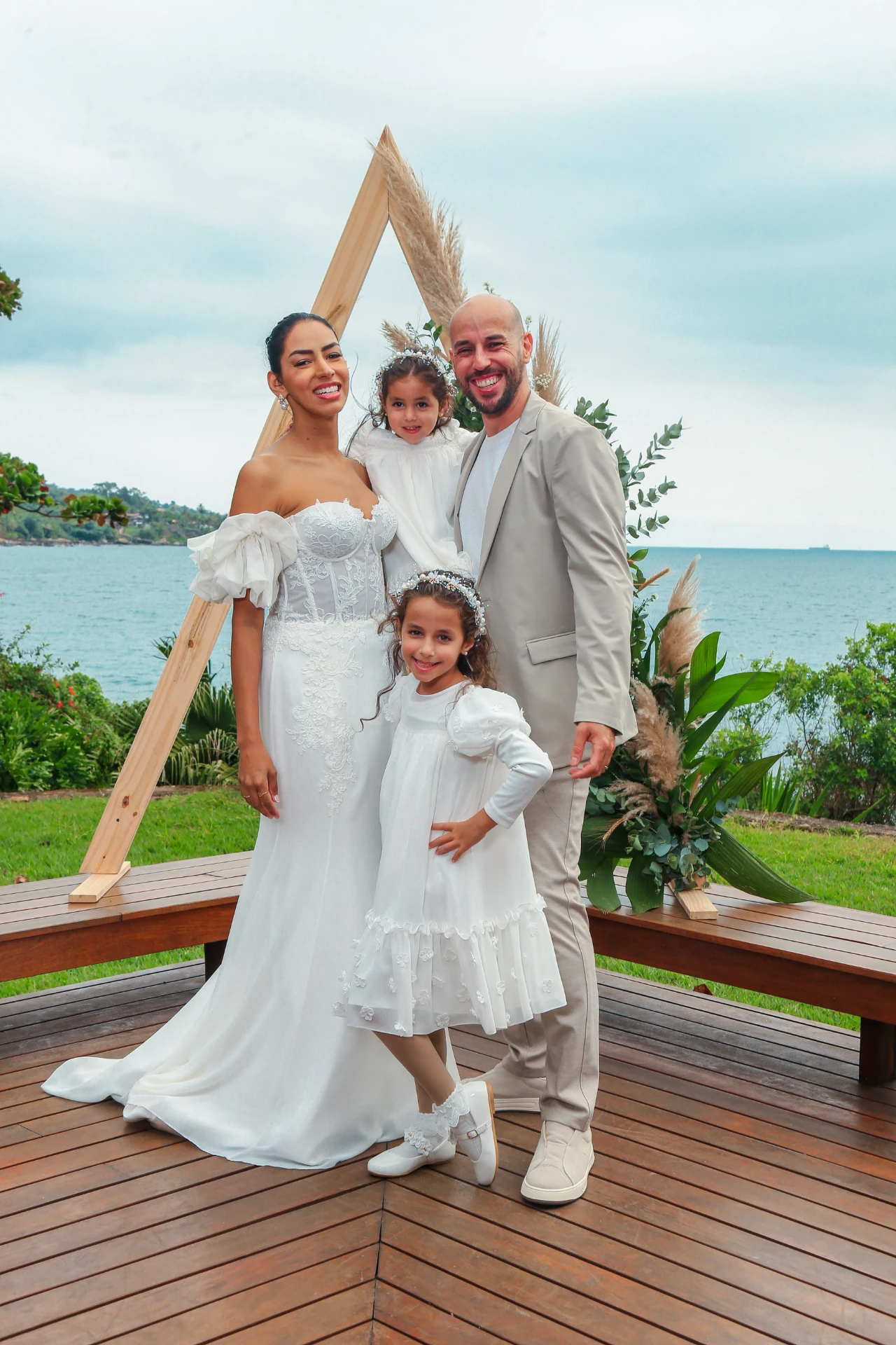 Larissa e Roberto — os noivos com as duas daminhas posando no altar