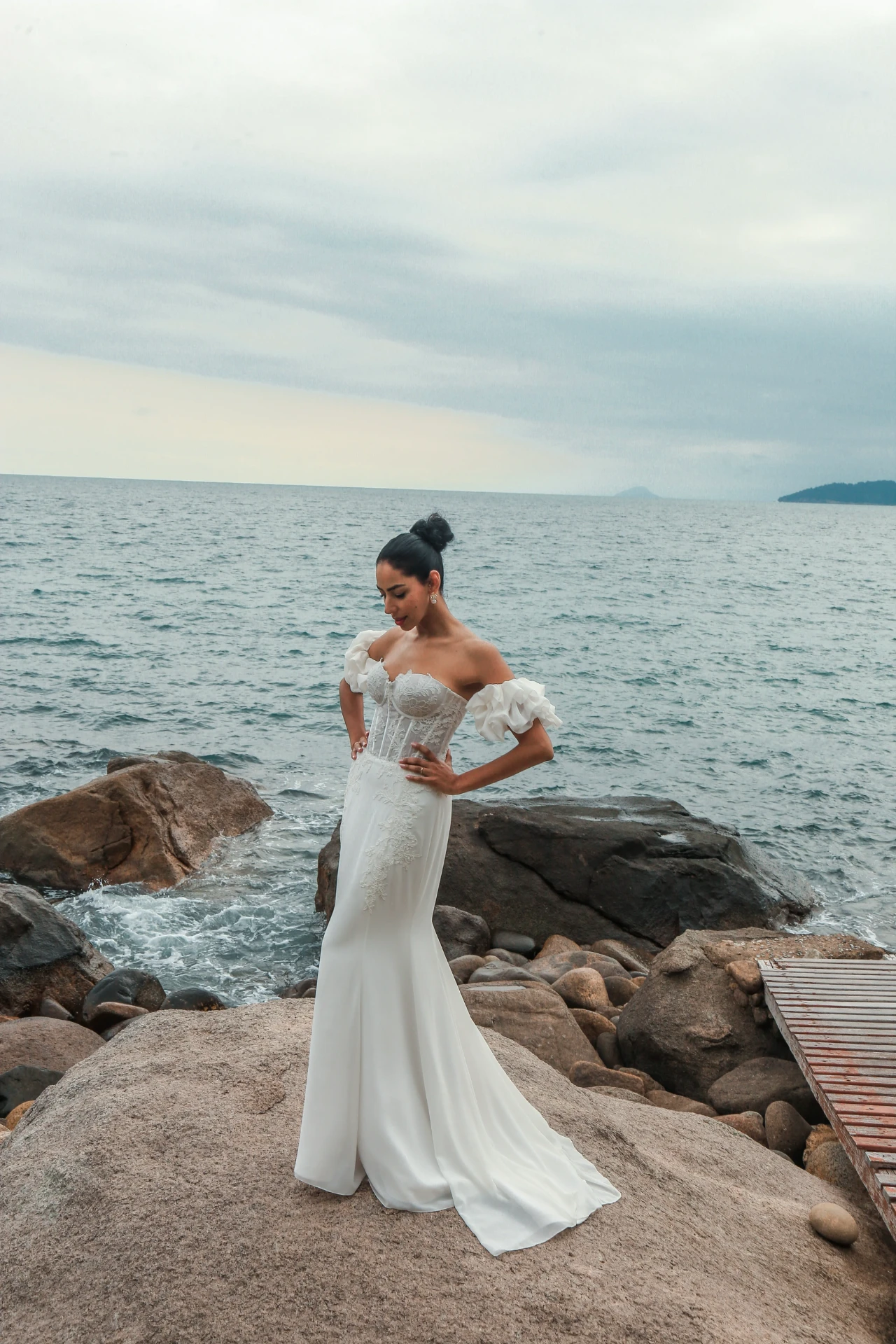 Larissa e Roberto — noiva olhando para o vestido na costa rochosa