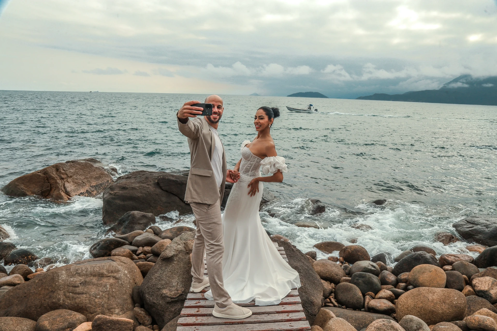 Larissa e Roberto — noivos fazendo uma selfie na passarela à beira-mar