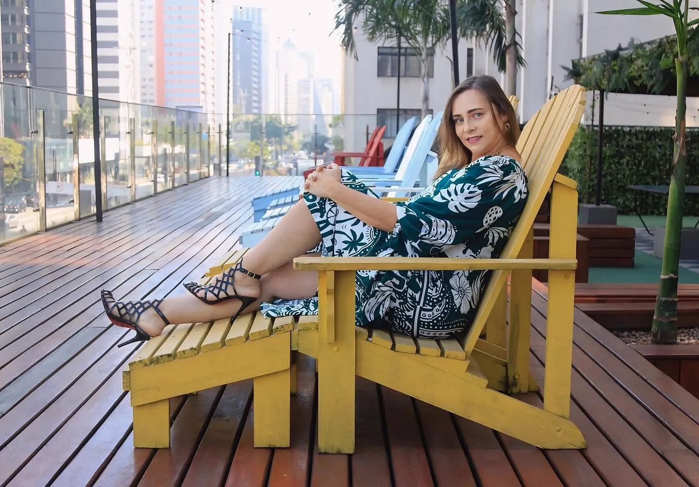 Retrato sênior — mulher em cadeira amarela com vista para os prédios da Avenida Paulista