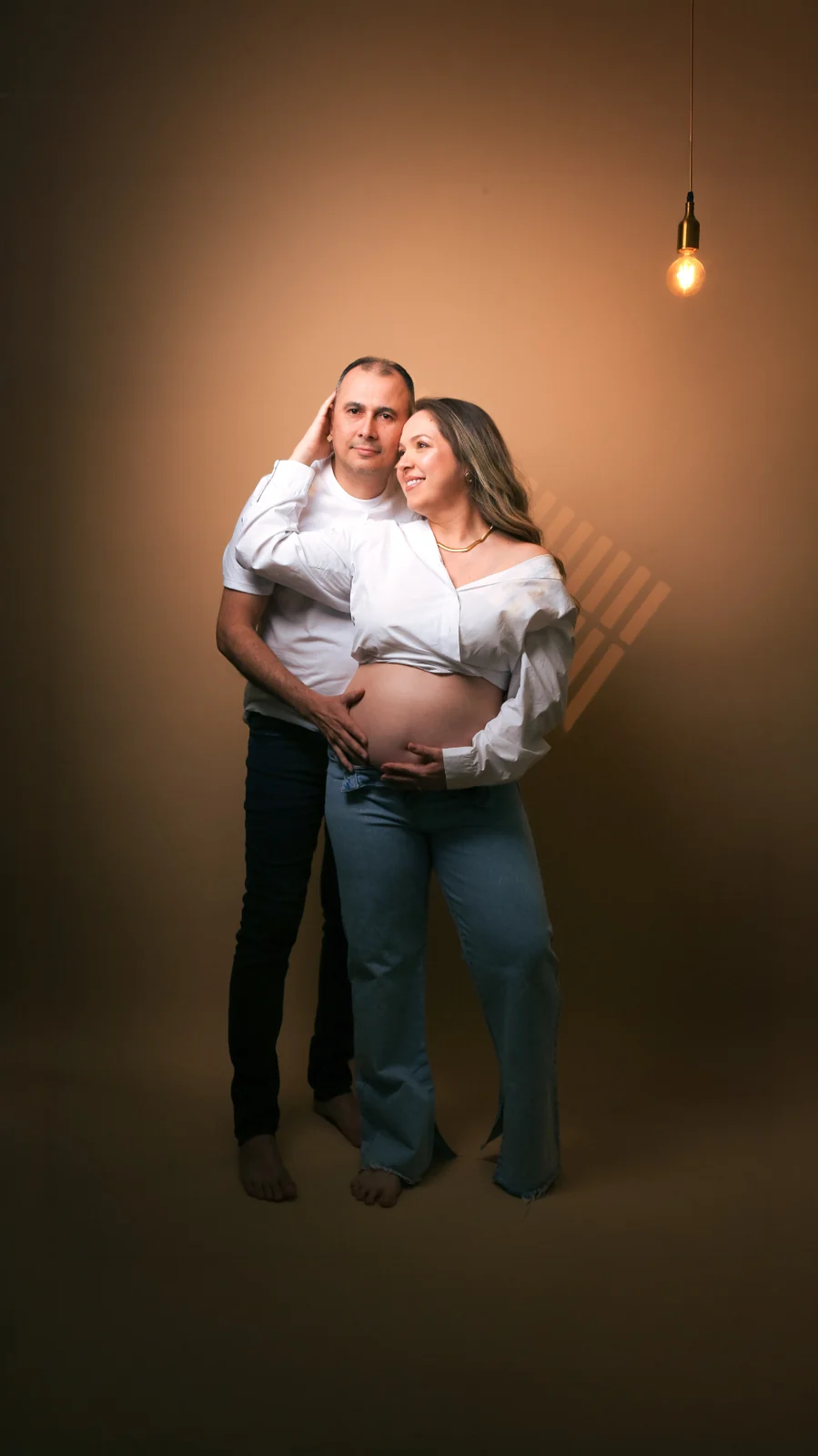 Deborah e Wellington abraçados de pé sob uma lâmpada quente