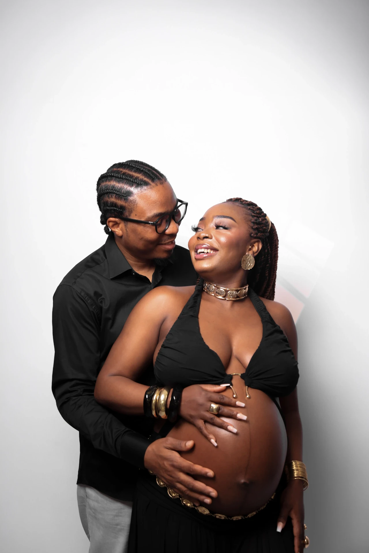 Casal se olhando com as mãos na barriga da gestante