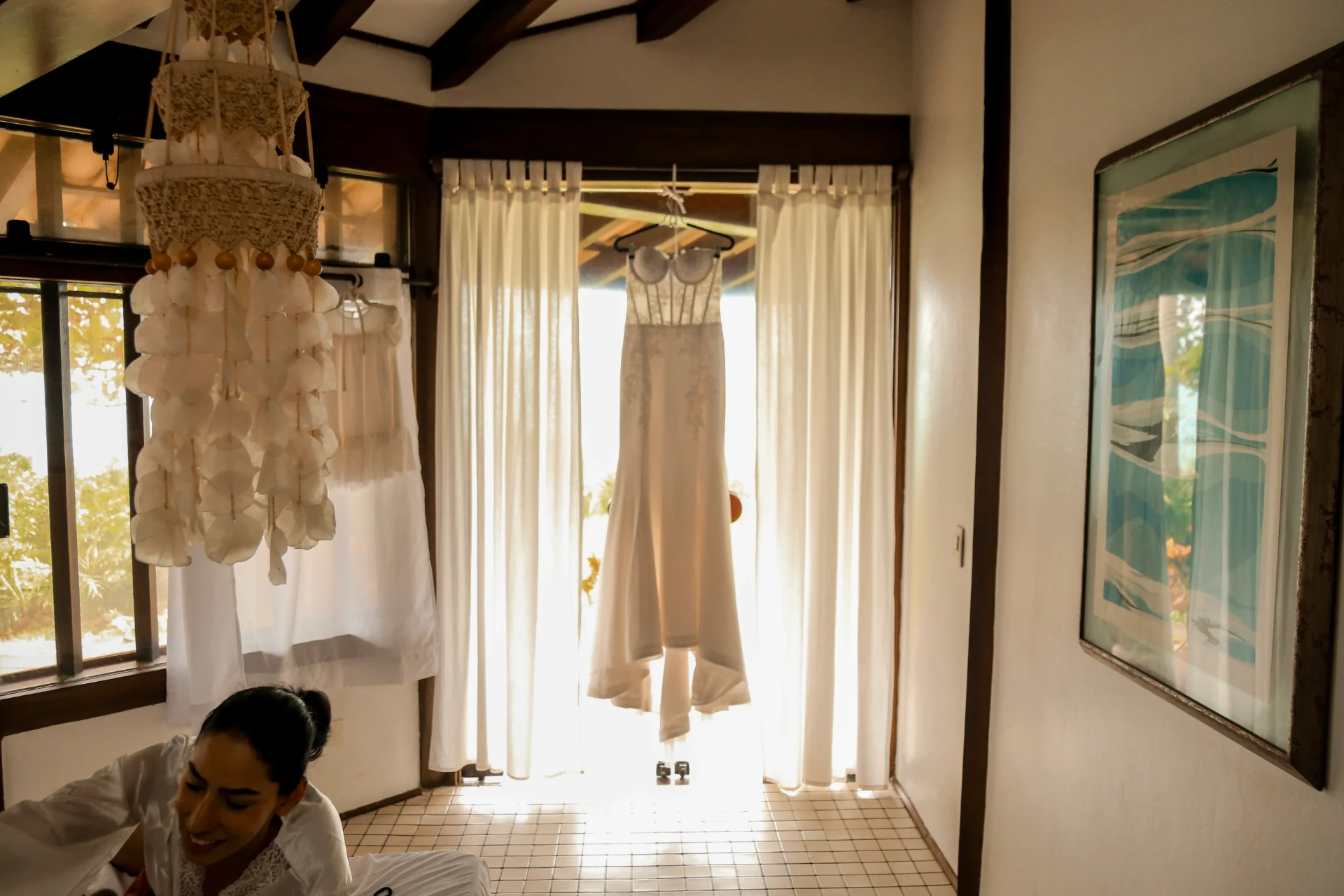 Larissa e Roberto — Vestido de noiva pendurado na porta iluminada pelo sol