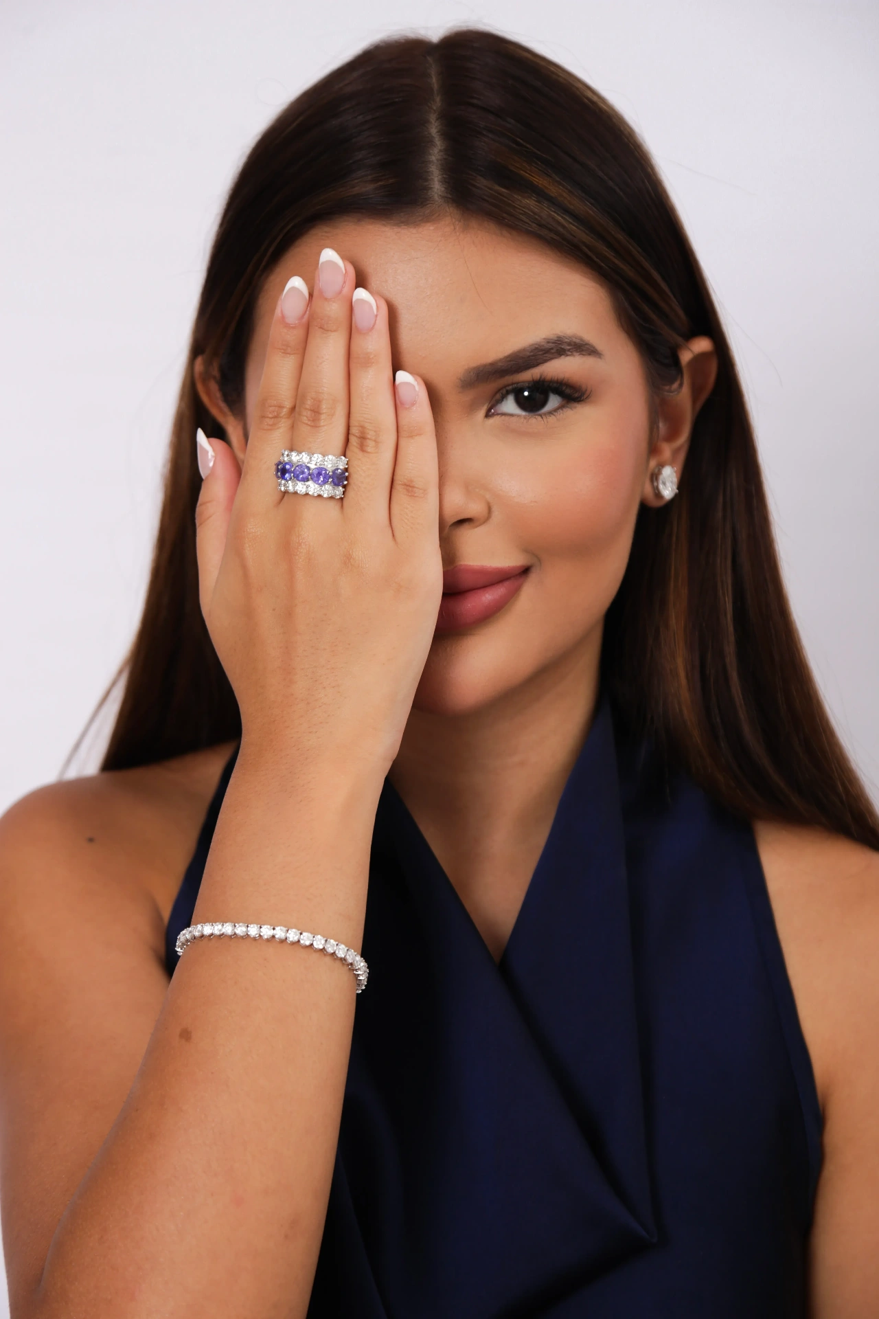 Fina Jolie modelo cobrindo o olho exibindo anel de tanzanita e pulseira
